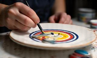 Un'artista decora un piatto di ceramica con un pennello fine.